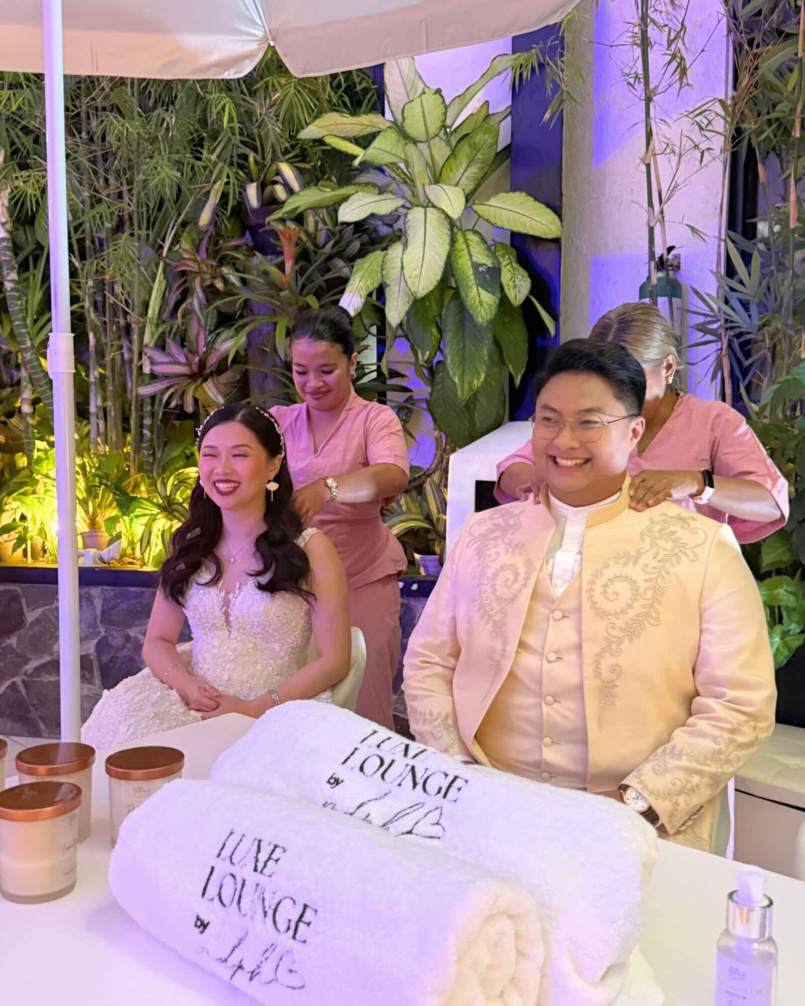 Bride and groom enjoying seated massages together at their wedding celebration